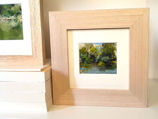 Small landscape oil painting of a silvery calm river with reflections of forest.