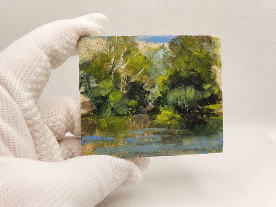 Small landscape oil painting of a silvery calm river with reflections of forest.