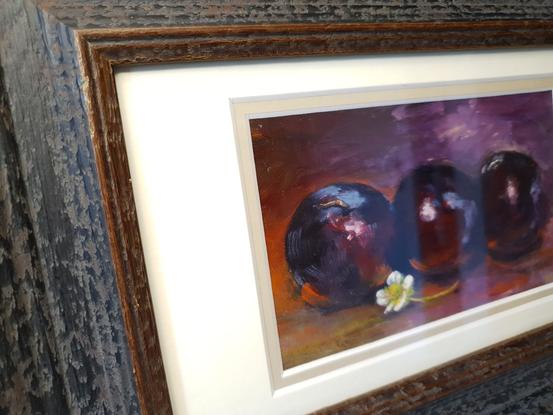 small still life of three pears on dark background highlighted in mauve, with white strawberry flower