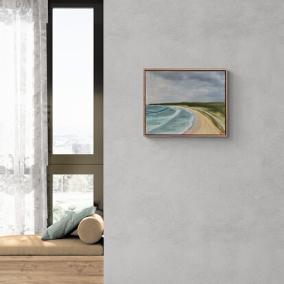 An elevated view of surf, sand, and green headland under a stormy sky