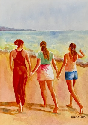 Women walk together on the beach.