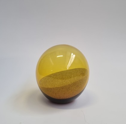 A blown glass golden sphere holding a memento of the golden sand of the Australian beach