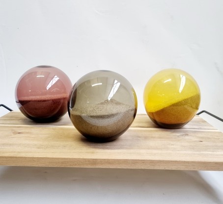 A blown glass golden sphere holding a memento of the golden sand of the Australian beach