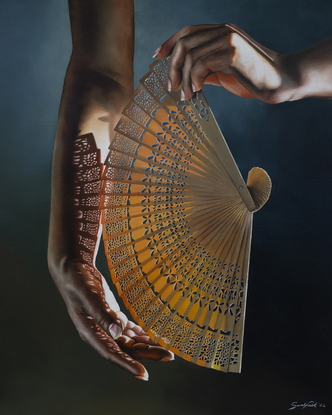 Hand holding an intricate fan with light streaming through the fan, casting a pattern of shadows across the hand.