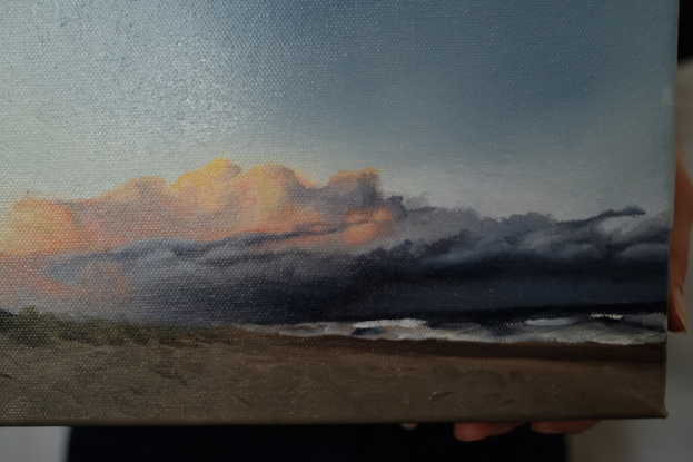 Small oil painting of the beach, with brooding clouds in the distance. 