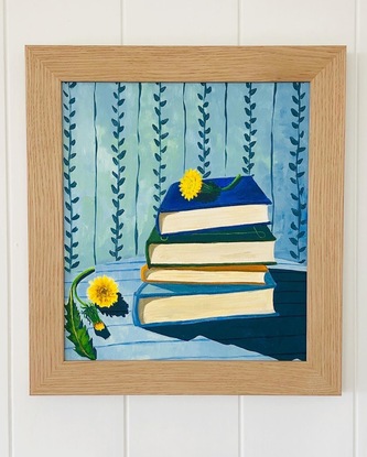 Pile of books on a striped blue tablecloth, with dandelions and vine wallpaper behind. 