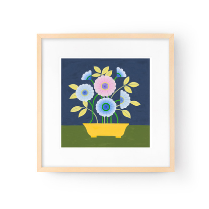 Bunch of blue and purple daisy flowers extending from bright yellow pot sitting on olive green table with navy wall behind.