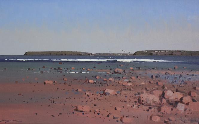 Beach scene with rocks and surf under a blue sky.