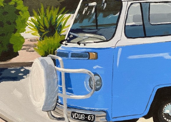 Blue Kombi van in carpark near large trees, both casting strong shadows in the foreground with hint of ocean in the background under and clear blue sky. 