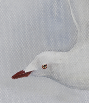 White seagull flying against grey sky.