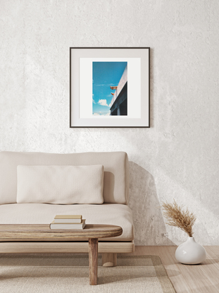 An angled view of a concrete wall and two pairs of feet propped up hanging over against a bright blue sky.