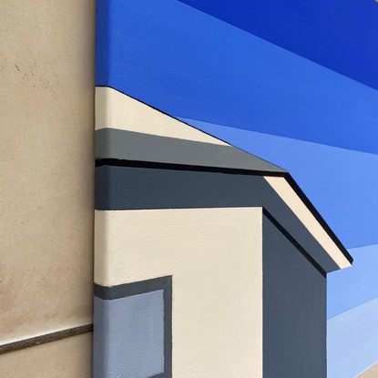 Simple cream/beige coloured house facing bright sun with side wall in shadow before striped, geometric blue sky.