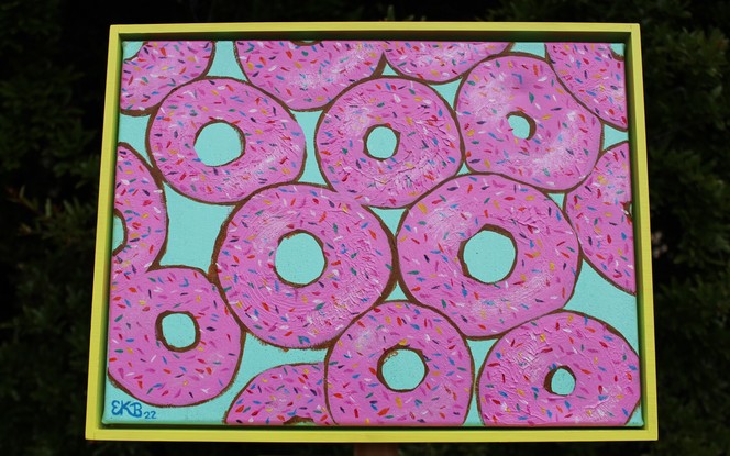 Donuts printed in pink with sprinkles on a turquoise glitter background.