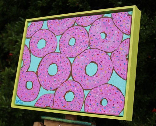 Donuts printed in pink with sprinkles on a turquoise glitter background.