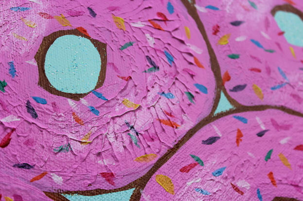 Donuts printed in pink with sprinkles on a turquoise glitter background.