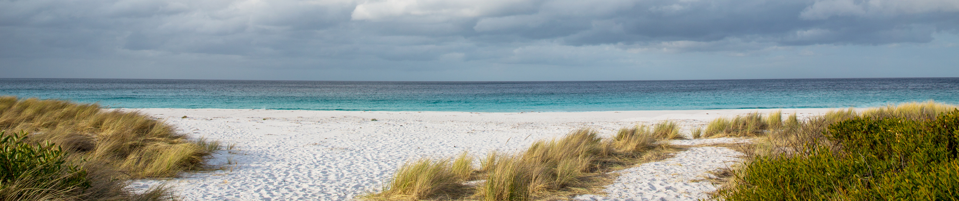 Blue sky, white clouds, blue water, white sand, and green grasses.