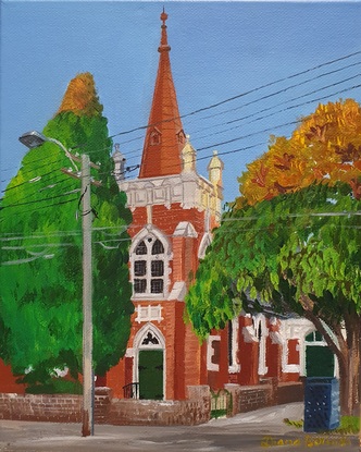 Old red brick church in afternoon light with trees around it.