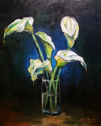 Multiple white flowers are placed within a transparent glass cup filled with water. The flowers are shaped like bells or cups as well. The cup of flowers is in front of a dark background.