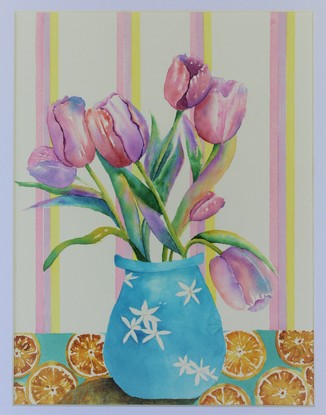 Vibrant pink and purple tulips, in a blue vase sitting on a table, with a citrus tablecloth.