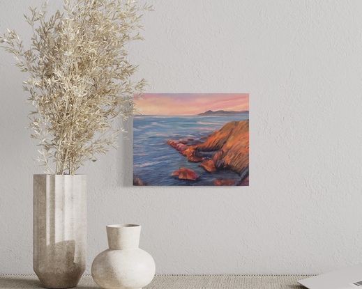 Sunrise oil painting with bright orange rocks lit up by the warm morning sun, contrasting with the cool blues of the ocean and the pink and orange sky on the distance.