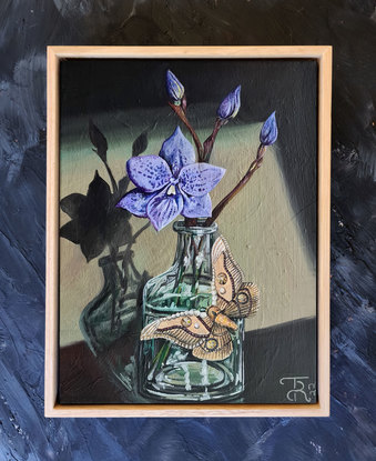 Flower in a glass vase with a moth.