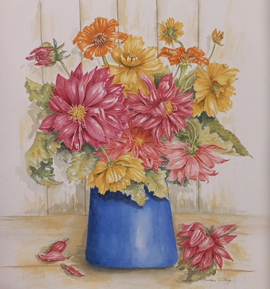 Red, orange and yellow spring flowers with green and brown tinted foliage in a blue vase