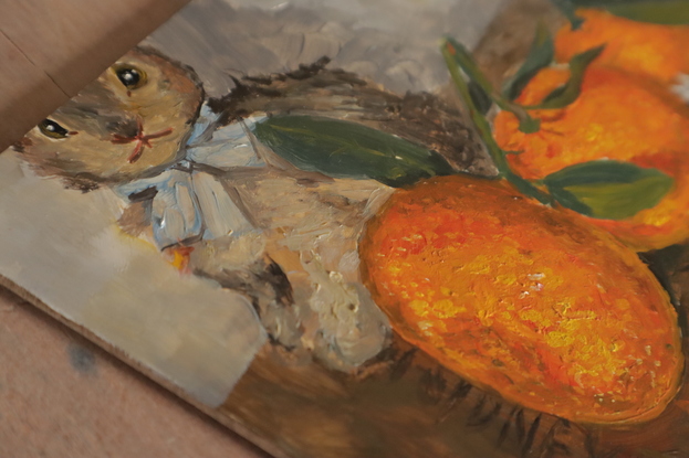 Impressionistic painting of a grey bunny on a Fry's Homeopathic Cocoa wooden box. In front of them sits 3 beautiful mandarin oranges, with stems and leaves, and a silver medieval replica pin  which is of a cat with a mouse in its mouth, it reads "vi sis mis" - I have the mouse.