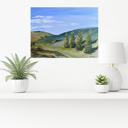 This country landscape depicts olling green hills and a row of trees, a winding dirt track and rocky outcrops under a hazy blue sky. 