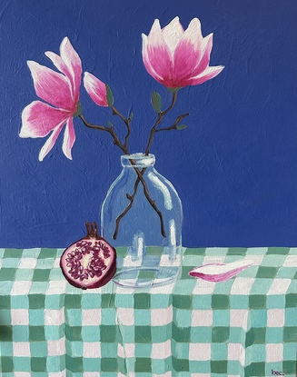 A still life depicting - a glass vase with two magnolia flowers and buds, a pomegranate leaning against the vase and a single fallen petal sitting nestled into the gingham creased table cloth. With a bold pacific blue backdrop 