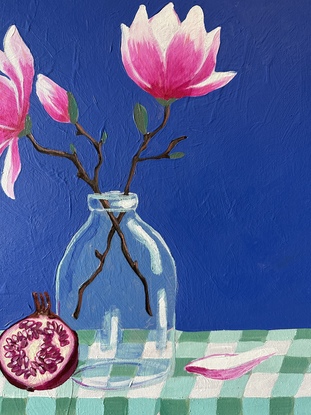 A still life depicting - a glass vase with two magnolia flowers and buds, a pomegranate leaning against the vase and a single fallen petal sitting nestled into the gingham creased table cloth. With a bold pacific blue backdrop 