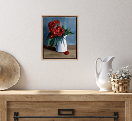 Red flowering gum blossoms in a white vase. 