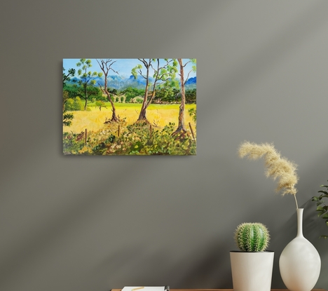 a painting of a field of golden pastures interspersed with shrubs and gum trees with the rugged cliffs in the background, with undulating slopes and a rugged fence line in the midst with cows going about their  daily routine looking for something to munch on.