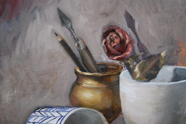 A cluster of objects, featuring a cup and saucer, an overturned cup, a large coffee mug, a spent tube of paint, a zippo lighter, a palette knife, a pencil, a dried rose and an old style folding pocket knife. The lighting is balanced and the background looks almost misty and ethereal, contrasting the detailed rendering of the subject matter.  