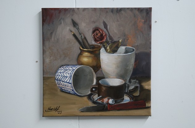 A cluster of objects, featuring a cup and saucer, an overturned cup, a large coffee mug, a spent tube of paint, a zippo lighter, a palette knife, a pencil, a dried rose and an old style folding pocket knife. The lighting is balanced and the background looks almost misty and ethereal, contrasting the detailed rendering of the subject matter.  