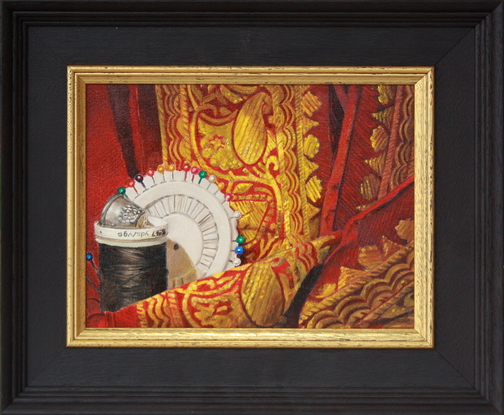 A thimble sits atop a spool of black thread against which rests a circular holder of dressmaker's pins. The articles are entwined with red and gold silk.