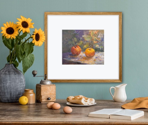 A Still Life depicting in bright colours. An apple and an orange surrounded by leaves on a table cloth. 