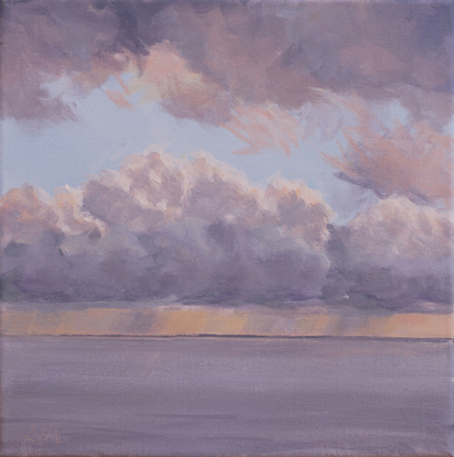 Dramatic grey clouds rise above a calm sea. Beneath the them a band of orange hints at the sunset while the light blue glimpses appear above. 