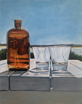 An amber bottle stands on a white table with two empty clear water glasses with a glimpse of the ocean and blue sky in the background.