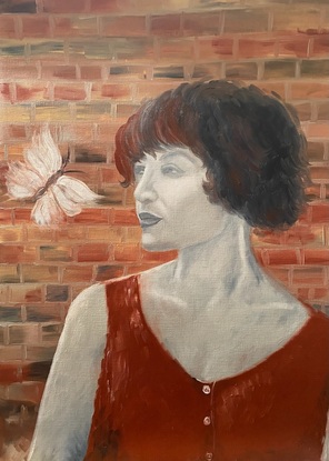 Woman in a red dress with a brick wall at the back, looking at a butterfly.