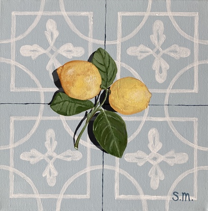 Two lemons, attached to their stems and resting on a powder blue encaustic tile background, accented by a contrasting shadow