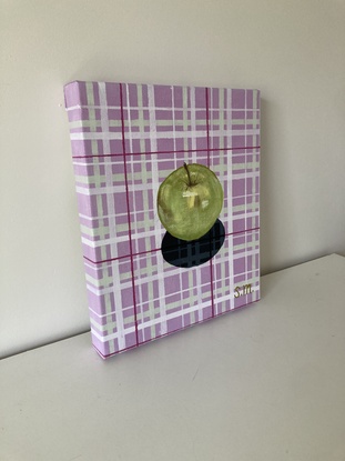 Granny Smith apple on lavender and sage green patterned plaid cloth with shadow detail