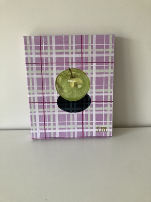 Granny Smith apple on lavender and sage green patterned plaid cloth with shadow detail