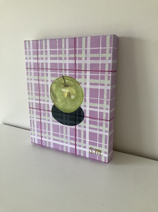 Granny Smith apple on lavender and sage green patterned plaid cloth with shadow detail