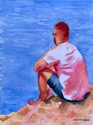 Man sits at the edge of the sea.