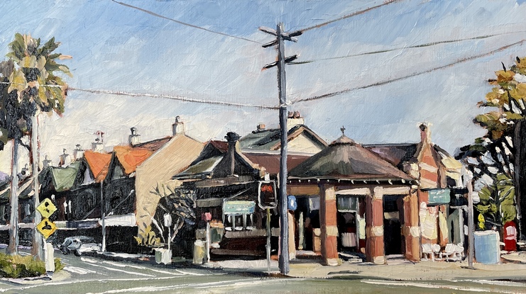 A street scene of the Strand, the main road through Croydon village. It shows the distinctive old post office which are prominent and iconic through many suburbs of the inner west of Sydney. The afternoon sun creates strong shadows off the two storey building of the street. To the left, a pair of a much longer row of palm trees frame the scene. 