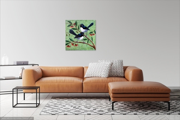 Two beautiful Willy Wagtails sitting on a eucalyptus tree with red and yellow gum blossoms. The background is a pale green speckled colour, with specks of yellow blossom sifting through the air.  The two birds appear to be in conversation.