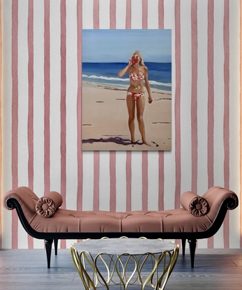 Bikini girl stands on beach holds a red hibiscus