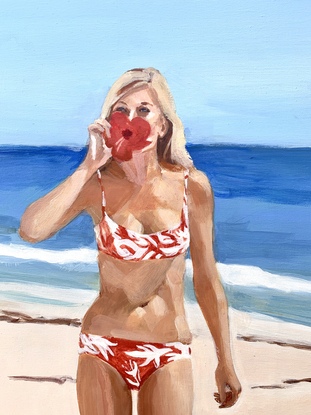 Bikini girl stands on beach holds a red hibiscus