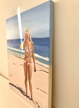 Bikini girl stands on beach holds a red hibiscus