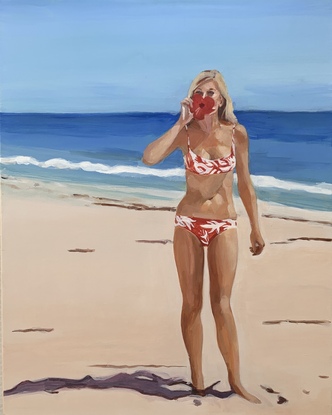 Bikini girl stands on beach holds a red hibiscus